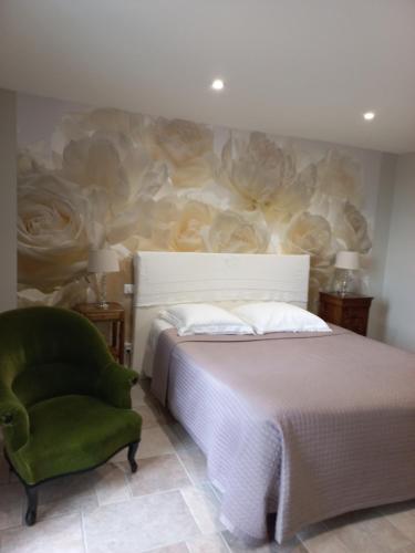 a bedroom with a bed and a green chair at L'Eglantyne in La Chapelle-de-Guinchay