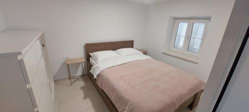 ein weißes Schlafzimmer mit einem Bett und einem Fenster in der Unterkunft Apartment by AntunovicWinery in Trpanj