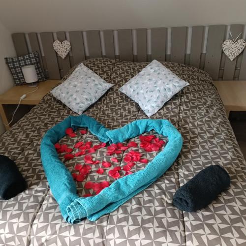 un cœur composé de roses rouges sur un lit dans l'établissement Au fil du Bonheur studio, à Surbourg