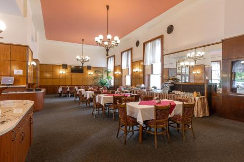 ein Esszimmer mit Tischen, Stühlen und Kronleuchtern in der Unterkunft Hotel Slovan Plzeň in Pilsen