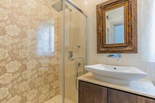 uma casa de banho com um lavatório e um chuveiro com um espelho. em Unique penthouse with private pool & sea view em St. Paul's Bay