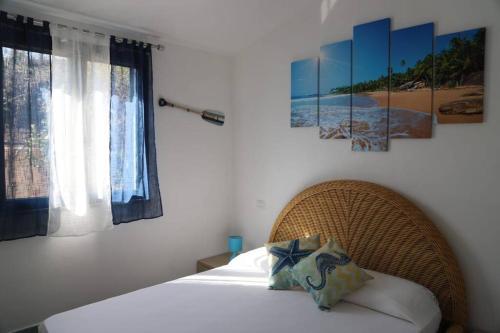 a bedroom with a bed and some paintings on the wall at Villetta Il Faro sul Mare in Àrbatax