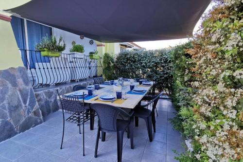 a table with chairs and an umbrella on a patio at Villetta Il Faro sul Mare in Àrbatax