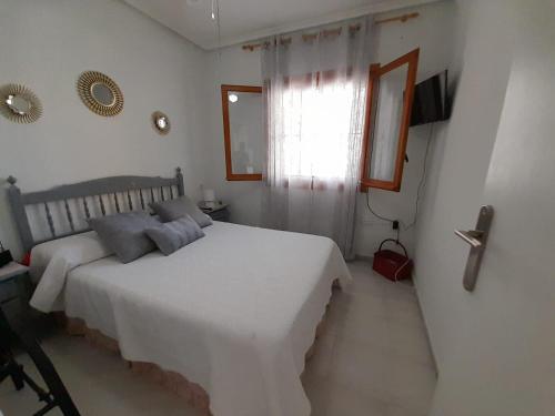 1 dormitorio con cama blanca y ventana en Apartamento en la playa, en La Mata
