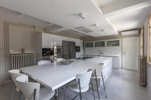 - une cuisine blanche avec une grande table et des chaises blanches dans l'établissement Villa Misano, au Mans