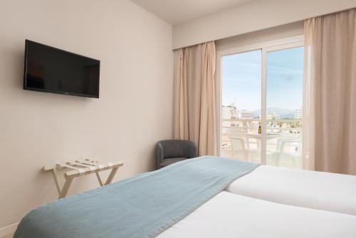 a hotel room with a bed and a large window at O7 Nordeste Playa in Can Picafort