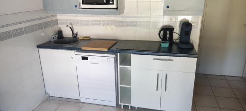 une cuisine avec des armoires blanches et un évier dans l'établissement Appartement T2 climatisé dans résidence calme, à Cavalaire-sur-Mer