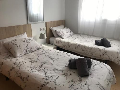 een slaapkamer met 2 bedden met witte en zwarte lakens bij Casa Bella in Murcia