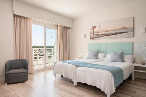 a bedroom with a large bed and a chair at O7 Nordeste Playa in Can Picafort