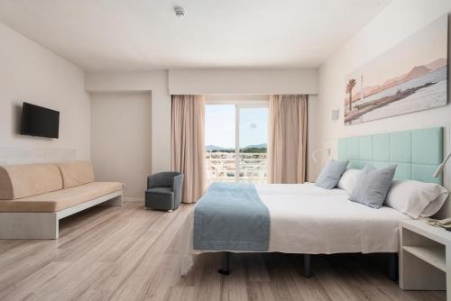 a bedroom with a large bed and a couch at O7 Nordeste Playa in Can Picafort