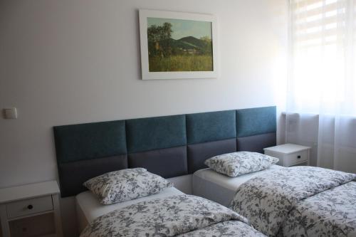 a bedroom with two beds and a picture on the wall at Apartament pod Miłkiem in Wojcieszów