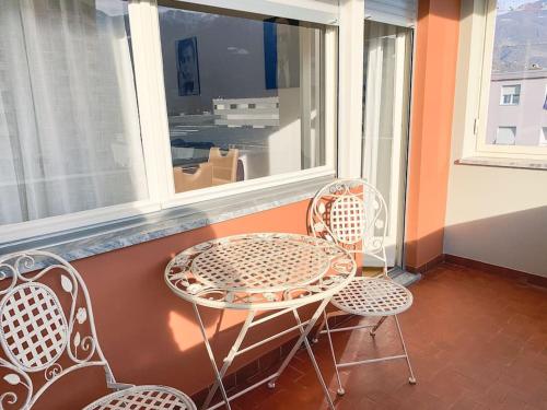 a table and two chairs on a balcony with a window at Vivere a Locarno - 5 minuti da Piazza Grande in Locarno