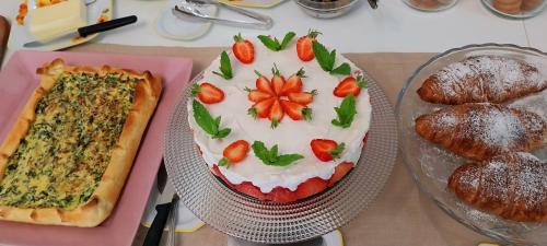 a cake with strawberries on it next to some pastries at Villa Bellavista Alba, B&B in Alba