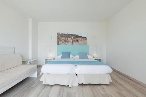 カン・ピカフォルトにあるNordeste Playaの白いベッドルーム(大型ベッド1台、ソファ付)