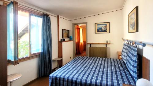um quarto com uma cama com um cobertor xadrez azul e branco em Charming traditional mountain house em Taceno