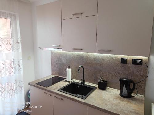 a kitchen counter with a sink and white cabinets at Moni 85 Family House in Sozopol