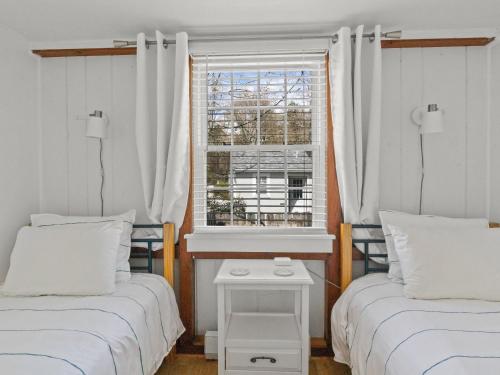 two beds in a room with a window at The Seagrove Suites & Guest Rooms in Eastham