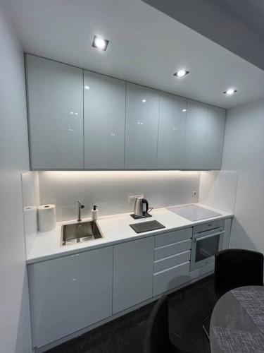 una cocina con armarios blancos y fregadero en Apartment Studio Morena, en Gdansk