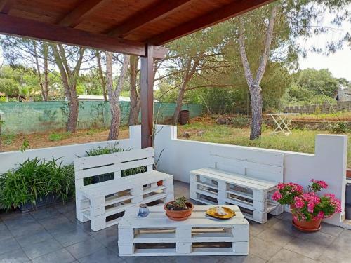 a patio with two white benches and a table at A Ca' Du Checchin in Carloforte