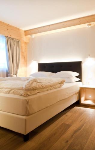 a large white bed in a room with a window at Chalet Le Coccole in Sappada