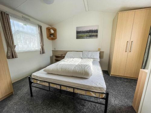 6 Berth Staycation Caravan Nearby Clacton-on-sea In Essex Ref 26254e في كلاكتون أون سي: غرفة نوم بسرير ونافذة