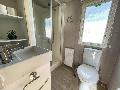 łazienka z toaletą, umywalką i oknem w obiekcie 6 Berth Staycation Caravan Nearby Clacton-on-sea In Essex Ref 26254e w mieście Clacton-on-Sea