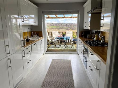 a kitchen with white cabinets and a view of a table at Gateway to the South Downs Near Brighton in Portslade