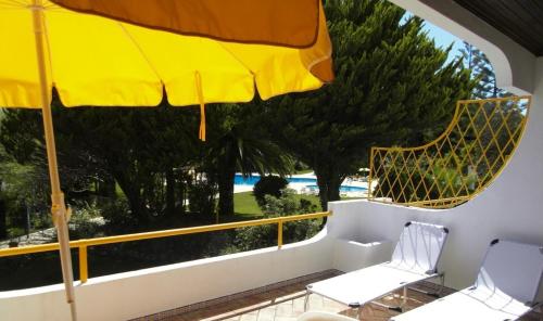een balkon met 2 stoelen en een parasol bij Golden Beach Vilamoura in Quarteira