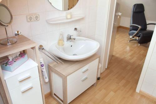 baño con lavabo, espejo y silla en Ferienwohnung Eifelmond, en Nettersheim