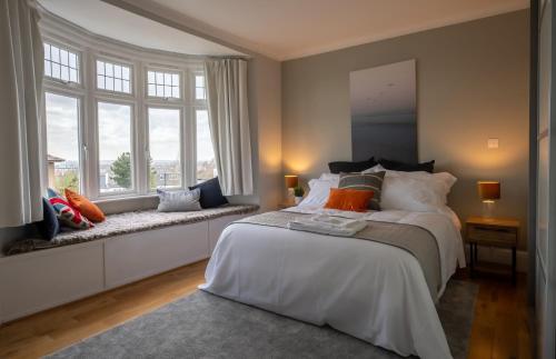 a bedroom with a large white bed and windows at Entire home in Streatham with lovely views & ultra fast Wi-Fi in Norbury