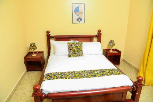 een slaapkamer met een houten bed met 2 nachtkastjes bij Palm Star Motel in Fort Portal