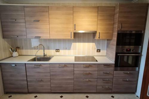 uma cozinha com armários de madeira e um lavatório em Apartamento Malzapatu - 4 dormitorios - Llanes em Llanes