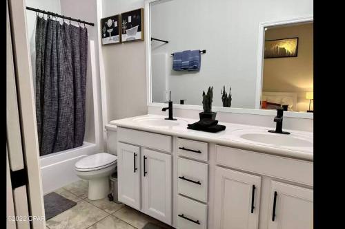 a bathroom with a sink and a toilet and a mirror at Vacation home next to the beach! in Panama City Beach