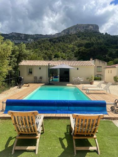 une piscine avec deux chaises et une maison dans l'établissement Studio de charme avec piscine, à Fontaine-de-Vaucluse