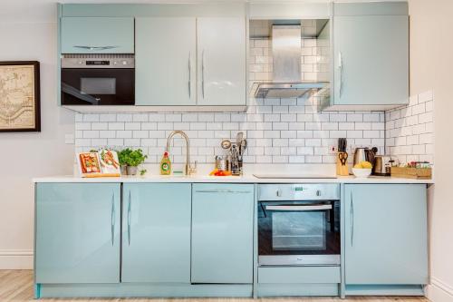 a kitchen with white appliances and blue cabinets at Nell Gwynn Chelsea Accommodation in London