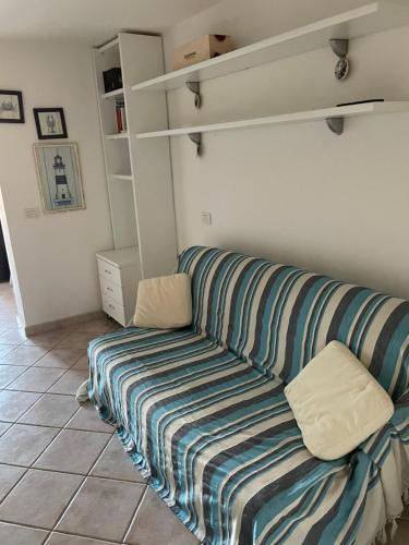 eine Couch mit gestreifter Decke in einem Zimmer in der Unterkunft Monolocale Cala Reale in Marinella