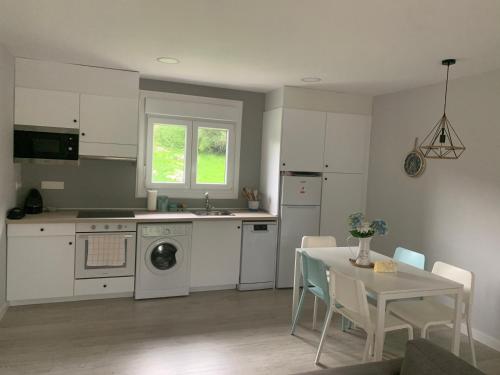 una cocina con electrodomésticos blancos y una mesa con sillas. en Apartamentos Cañamal en Llanes