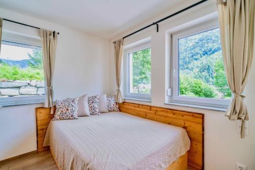 a bedroom with a bed and two windows at 1Schönes Ferienhaus im sonnigen Kärnten in Döbriach