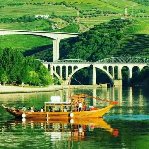 a yellow boat on the water in front of a bridge at Casa do Trovão - Douro in Peso da Régua