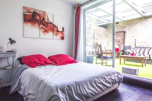 ein Schlafzimmer mit einem Bett mit roten Kissen darauf in der Unterkunft Appartement avec jardin intérieur 4 pers centre ville in Nemours