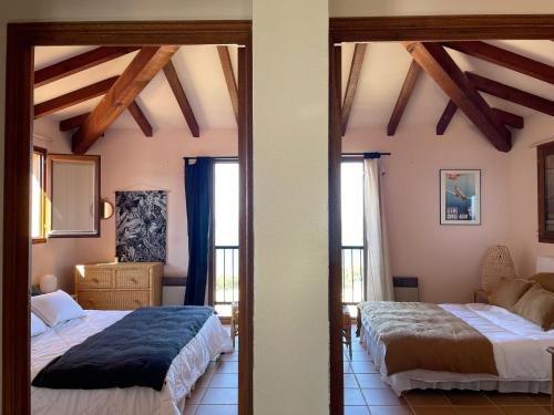 2 Betten in einem Zimmer mit Holzbalken in der Unterkunft Maison de Lou in Porticcio