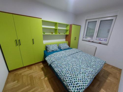 een slaapkamer met groene en gele kasten en een bed bij Apartman Green in Lukavica