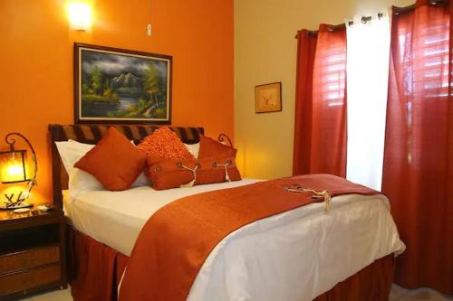a bedroom with a bed with orange walls at The Exoria Cottage in Ocho Rios