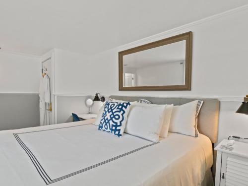 a white bedroom with a large bed with a mirror at The Seagrove Suites & Guest Rooms in Eastham