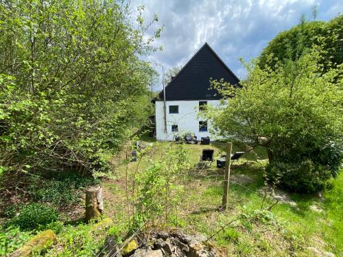 a white house with a black roof and trees at Urlaub in der Natur in Lüdenscheid