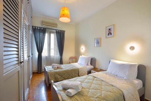 a hotel room with two beds and a window at Gardenia Suite Corfu Town in Corfu
