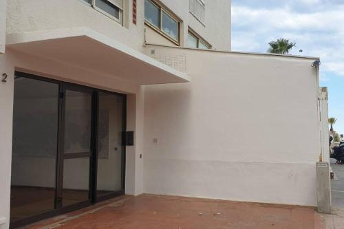 - un bâtiment blanc avec une grande porte en verre dans l'établissement Superbe appartement à 40 mètres de la plage, à Canet