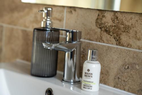 a bathroom sink with a bottle of soap next to a faucet at Entire home in Streatham with lovely views & ultra fast Wi-Fi in Norbury
