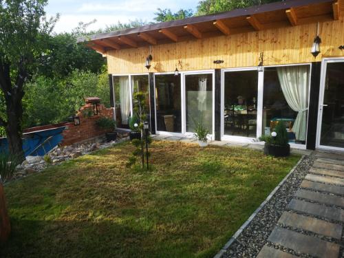a house with glass doors and a yard at The Little Blue House in Reşiţa