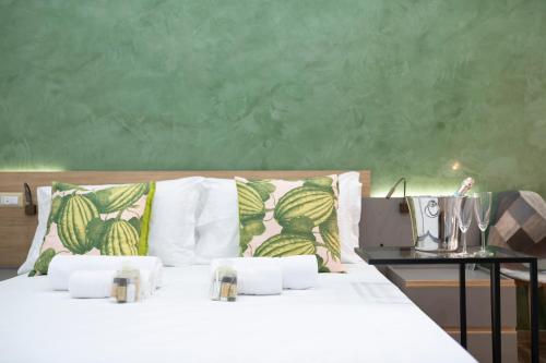a bed with white pillows and a green wall at Catone Luxury Rooms in Rome